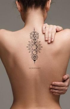 the back of a woman's neck with an intricate tattoo design on her left shoulder