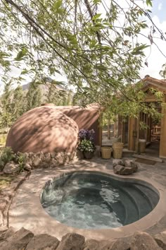 a hot tub in the middle of a patio next to a tree and some rocks