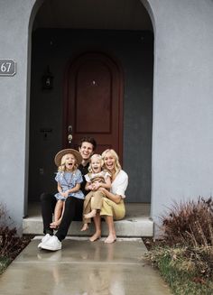 a family sitting on the front steps of a house