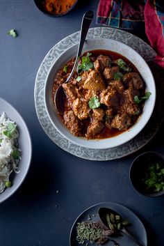 two bowls of food on a table with spoons and plates full of rice next to each other