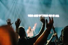 a group of people raising their hands up in the air at a concert or show