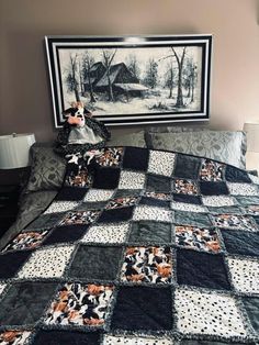 a black and white quilt on a bed in a room with a painting above it