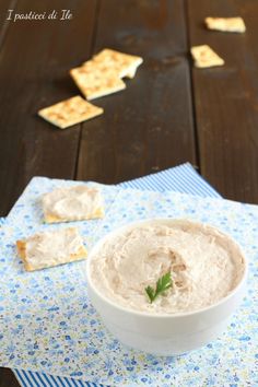 a white bowl filled with hummus and crackers on top of a blue napkin