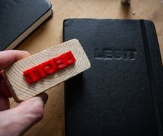 a person holding a piece of wood with the word igei carved into it