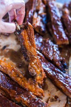 someone is dipping ribs into some sauce on top of the bbq meats that are being cooked