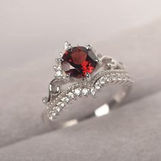 a close up view of a ring with a red stone and white diamonds on it