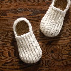 two crocheted white slippers sitting on top of a wooden floor next to each other