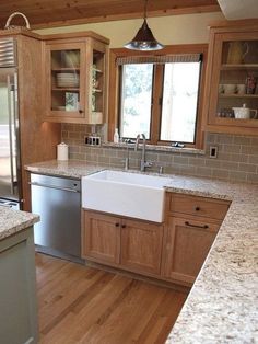 a kitchen with wooden cabinets and granite counter tops, stainless steel dishwasher on the center island