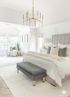 a large bed sitting in a bedroom next to a chandelier