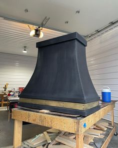 a large black stove top sitting on top of a wooden pallet next to a white wall