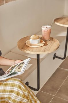 a woman sitting at a table reading a magazine