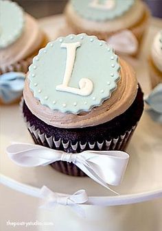 cupcakes decorated with blue and white icing are sitting on a cake plate