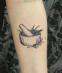 a black and white photo of a tattoo with herbs in a mortar bowl on the arm