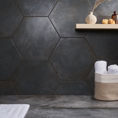 a bathroom with hexagonal tiles on the wall and white towels in a basket