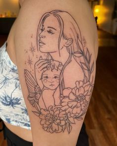 a woman with a tattoo on her arm holding a baby and an angel above her head