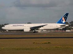 an airplane that is sitting on the tarmac at an airport with grass and trees in the background