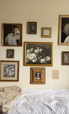 a bed with white sheets and pictures on the wall next to it in a bedroom