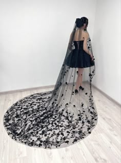 a woman in a black dress is standing on the floor with a veil over her head