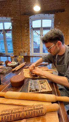 a man sitting at a wooden table working on some type of item in front of him