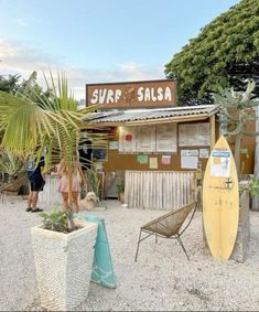 a surf shop with a yellow surfboard next to it and two people standing outside