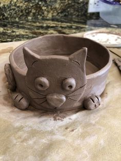 a clay cat bowl sitting on top of a counter