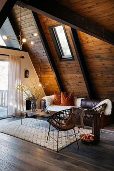 an attic living room with wood paneling and leather furniture, along with a rug on the floor