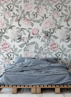 a bed sitting on top of a wooden pallet in front of a floral wallpaper