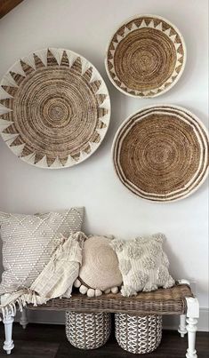 three woven baskets are hanging on the wall above a bench with pillows and throw pillows