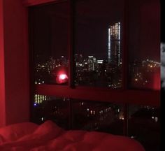 a red light shines in the window of a room overlooking a city at night