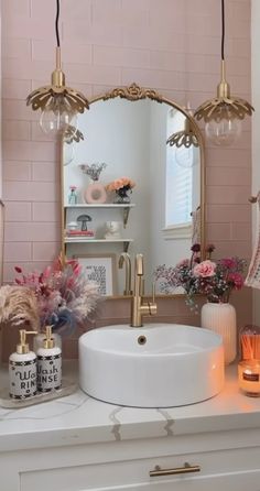 a white sink sitting under a bathroom mirror next to a pink tiled wall with flowers on it