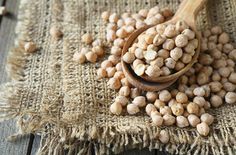 a wooden spoon filled with chickpeas on top of a table