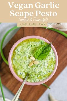 a small pink bowl filled with pesto sauce and topped with green leafy garnish