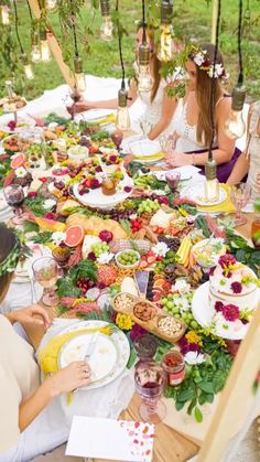 a group of people sitting around a table covered in food