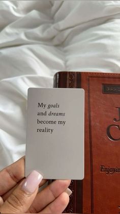 a person holding up a book in front of a white sheet with the words, my goals and dreams become my reality