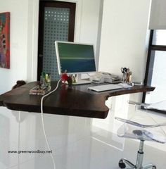 a desk with a computer on it in the middle of a white room next to a window