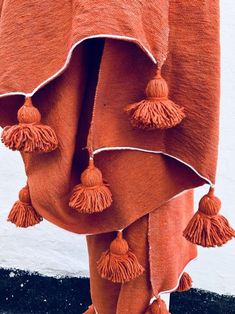 an orange blanket with tassels hanging from it's sides and on the ground