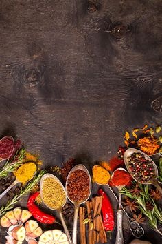 an assortment of spices and seasonings arranged in a circle on a wooden table with spoons