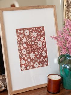 a vase with flowers next to a framed print