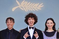 three people standing next to each other wearing tuxedos