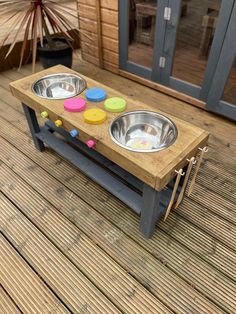 two metal bowls on a wooden table with colored buttons in front of a glass door