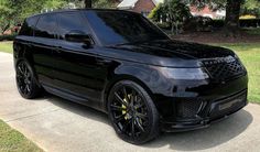 a black range rover parked on the side of a road in front of a house