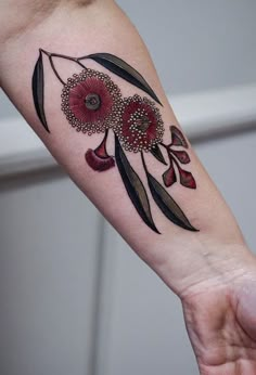 a woman's arm with flowers and leaves on the left side of her arm