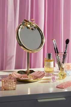 a vanity with makeup and other items on it, including a mirror that has been placed on the table