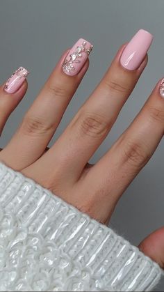 a woman's hand with pink and white nail polishes on her nails, in front of a gray background