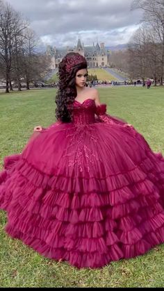 a woman in a red dress is sitting on the grass with her hands behind her back