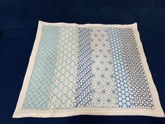 a blue and white table cloth with circles on it, sitting on a black surface