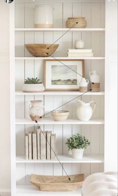 a white book shelf filled with books and vases