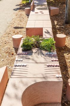 a bench made out of bricks with plants in the middle and rocks on each side