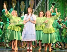 a group of women standing on top of a stage with their arms in the air