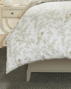 the bed is made with white linens and has a floral print comforter on it